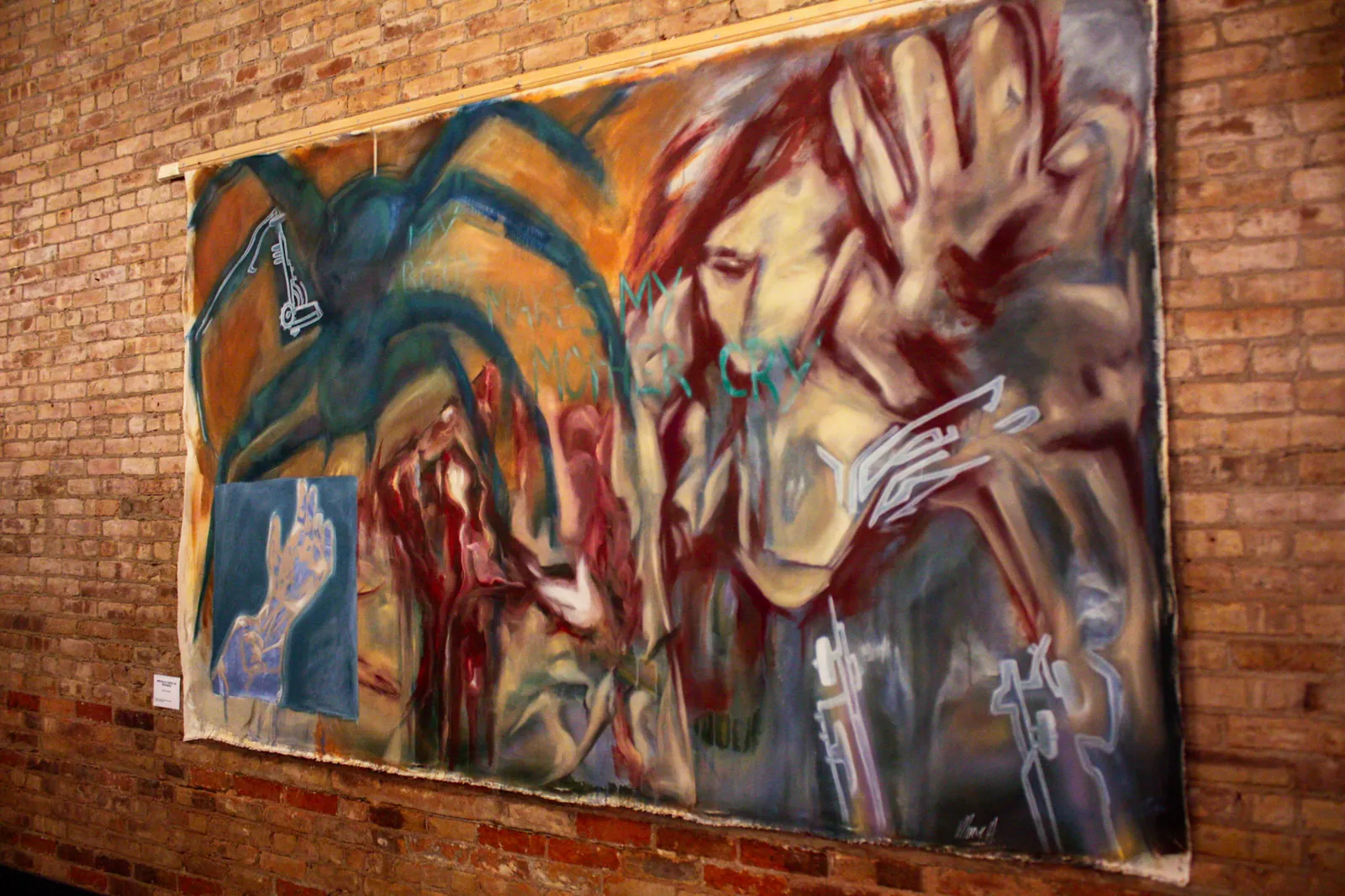 A very large unstretched canvas hung on the brick wall: figures in red, ochre and blue-green, the words 'my body makes my mother cry' written across it.