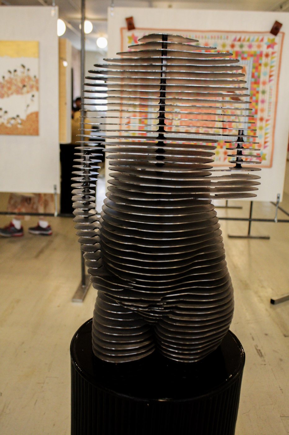 Waiting for You by Priscilla Smith: a pregnant torso built from thin horizontal slices of steel, stacked with narrow gaps between them, on a black plinth