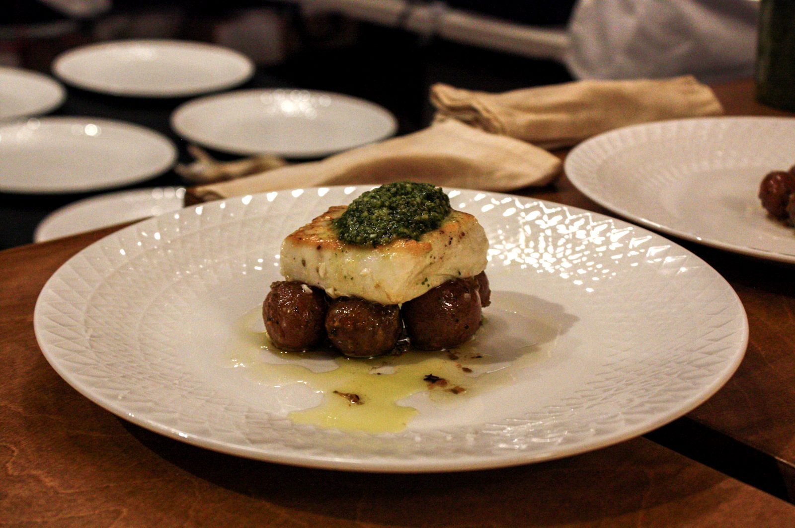 Atlantic halibut with dill pesto on citrus potatoes, on a white textured plate