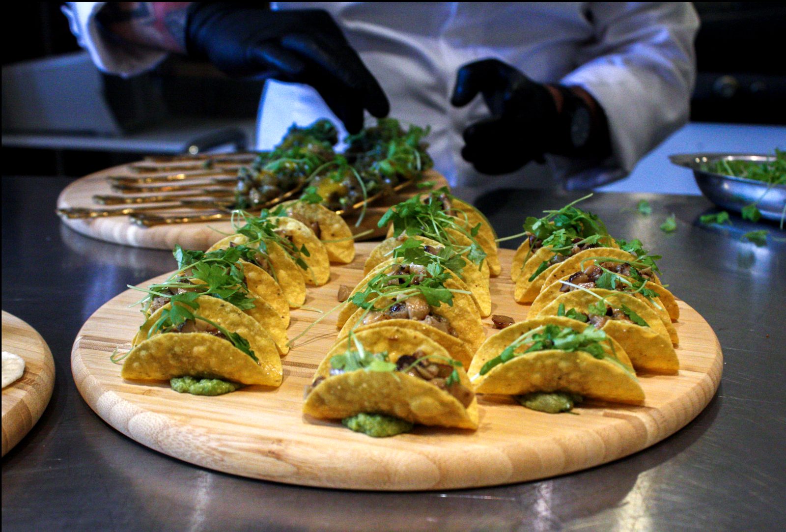 Rows of mini taco shells filled with wild mushrooms and topped with greens