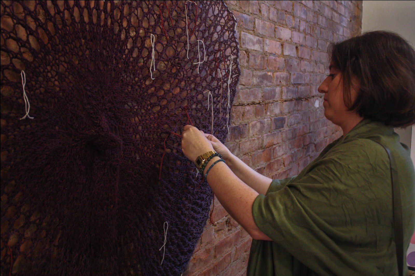 A visitor ties a length of colored thread into the knitted work at the exhibition